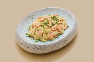 Risoni pasta mixed with tender shrimp is presented on a stylish plate. The dish is topped with
