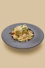 Delicious creamy garlic shrimp pasta rests artfully on a dark plate. The pasta showcases tender