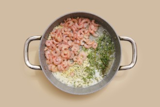 Shrimps and herbs sizzle in a pan, blending with chopped garlic, ginger and olive oil. Process of