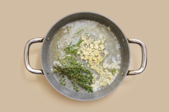 Butter and olive oil are heating in a pan with finely chopped garlic, ginger and fresh thyme and