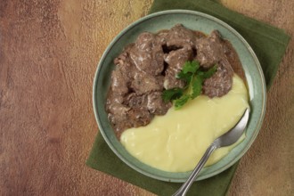 Liver beef stroganoff with mashed potatoes, table setting in green tones, homemade