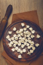 Traditional Turkish dumplings, raw, on a cutting board, top view, no people