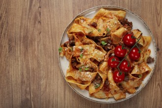 Pappardelle pasta with bolognese sauce, topped with parmesan cheese and cherry branch, homemade, no