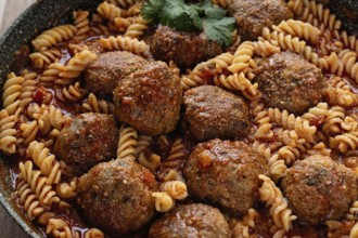 Minced meat meatballs, in tomato sauce, with fusilli pasta, in a cast-iron pan, homemade, no people