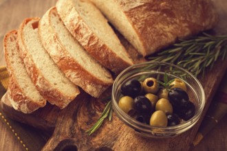 Sliced ciabatta, on a chopping board, with rosemary and olives, Italian bread, close-up, Italian