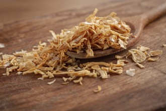 Smoked onion flakes, on a wooden spoon, wooden table, close-up