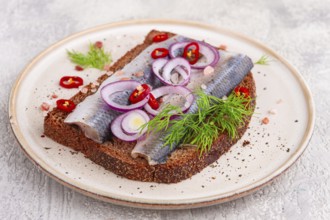 Sandwiches, Herring fish, on dark rye bread, sprinkled with onion, chili pepper and herbs, on a