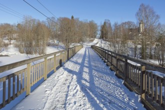 Old wooden walk bridge over river Koskenkylänjoki on a sunny winter day with snow covering the