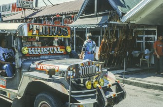 Jeepney minibus in front of a restaurant with skewered suckling pig, Lechon, Manila in 1995,