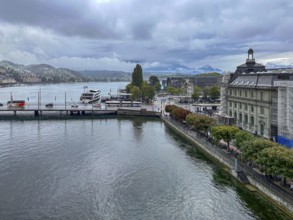 View of waterfront with boats and mountains in the background under cloudy sky, Lucerne,