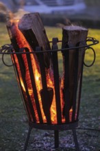 Burning logs in a fire basket create a warm, cozy atmosphere at dusk, North Rhine-Westphalia,