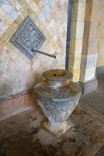 Close-up of an ancient well with mosaic decoration and detailed relief elements in stone
