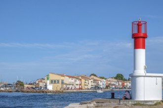 Men sitting at the red and white lighthouse at the port entrance of the Canal de Sete, formerly