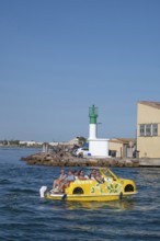 Sightseeing on the water: a yellow water car with tourists and lemon decorations rides on the Canal
