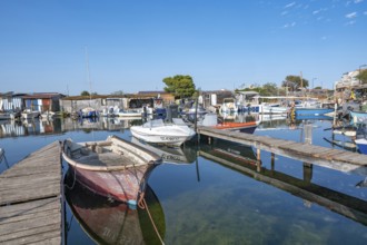 A red-faded fishing boat is moored on a wooden pier in the port of La Pointe Courte, whose