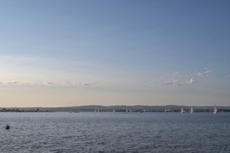 Wide-angle landscape view of Etang de Thau with several sailboats on the water sailing towards the