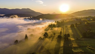Sunrise over a fog covered village in a rural landscape, golden morning light, serene autumn
