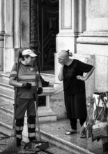 Black and white photography, street art, senior woman talking to a municipal cleaning employee,