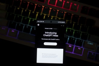 Smartphone with ChatGPT Atlas text in front of a backlit keyboard