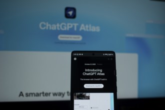 A smartphone highlighting ChatGPT Atlas in front of a blue screen