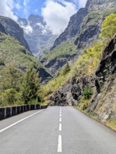 Winding road through mountains with towering peaks and a partly cloudy sky, La Réunion, France
