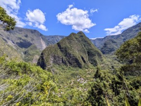 Towering green mountains overlooking a small village under a clear blue sky, La Réunion, France