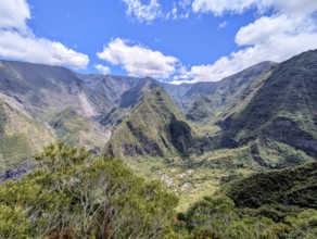 Majestic mountains with lush greenery under a bright blue sky and scattered clouds, La Réunion,
