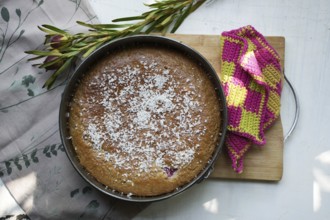 Coconut cake in an antique baking dish on a wooden board