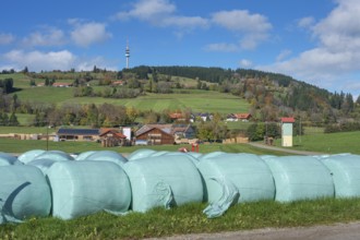 Blue sky with clouds, silage bales in front of the village of Masers under the mountain Blender