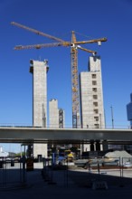 Yellow cranes on construction site of timber building Kaj 16 with hybrid concrete frames, sunny