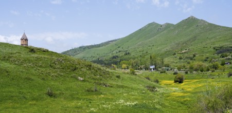 Small church on a green hill in front of picturesque mountains and blooming meadows, church,