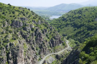 A green mountain landscape with rocks crossed by a road with a wide view of the valley, canyon of