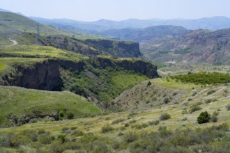 Deep gorge surrounded by green hills and mountains under bright skies, breathtaking scenery south