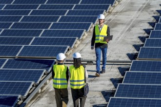 Engineers checking a large installation of solar panels on a commercial rooftop, ensuring optimal