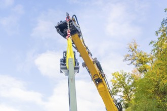 Yellow crane lifts a structure surrounded by trees, blue sky, Signalbau an der Hermann Hessebahn,