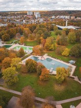 Autumn park with large trees and pond, surrounded by urban architecture, Sindelfingen, Böblingen