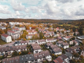 Residential area with terraced houses and surrounding colorful autumn trees in slightly cloudy