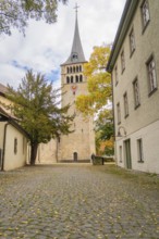 A narrow path leads to an old church tower with colorful autumn leaves, Sindelfingen, Böblingen
