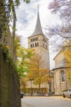 Historic church with high tower surrounded by autumn leaves and cloudy sky, Sindelfingen, Böblingen