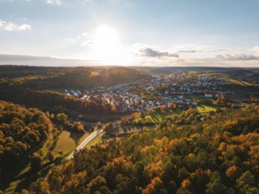Colourful autumn landscape with a view of a village and vast forests under the evening sun,