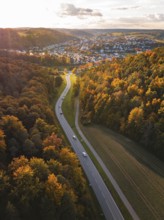 Road through autumn landscape with village in background during sunset, Aidlingen, Böblingen