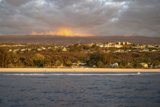The bright sandy beach of the Saint-Gilles lagoon with bathers merges into a coastal landscape with