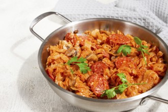 Polish dish bigos, in a stainless steel pan, stewed meat with cabbage, chorizo sausages, mushrooms,