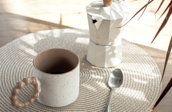 Making morning coffee, geyser coffee maker and mug, in bed colors, on a wooden table, natural