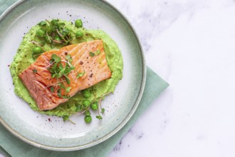 Delicious grilled salmon is placed elegantly on creamy green pea puree. Fresh microgreens and peas
