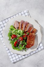 Grilled duck breast is beautifully presented beside a colorful salad of greens, cucumbers,