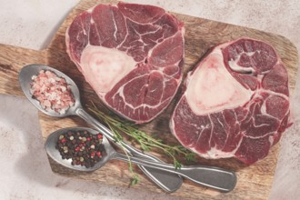 Knuckle on the bone, raw ossobuco meat, on a wooden chopping board, with spices, top view, no
