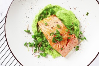 Delicious grilled salmon is placed elegantly on creamy green pea puree. Fresh microgreens and peas