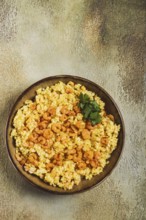 Risotto with shrimp, in a bowl, on a textured surface, with a side dish of fresh coriander,