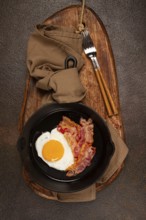 Fried egg with bacon, in a cast-iron pan, breakfast, top view, close-up, homemade, no people